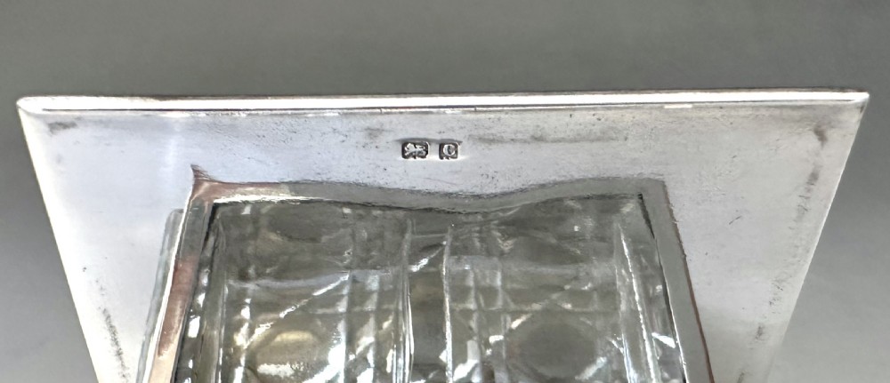 An Edwardian rectangular cut glass stamp box topped with a smooth sterling silver lid showing hallmarks along the rim. View IX