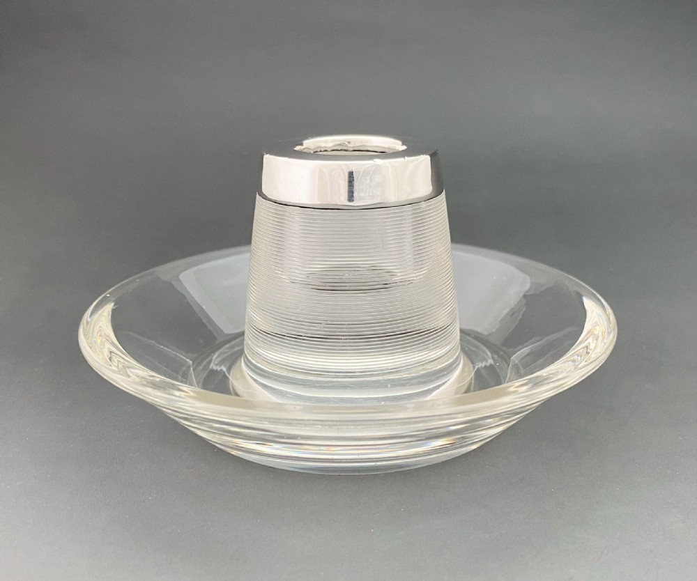 An Edwardian clear glass match striker featuring a ribbed cylindrical body, wide saucer base, and a hallmarked sterling silver collar holding red-tipped matches. View V