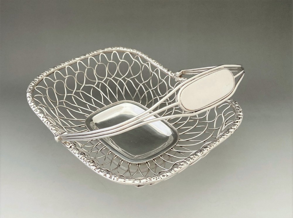 A Georgian silver-plated wirework basket featuring an arched swing handle, open lattice sides, and a polished solid central base. View VI