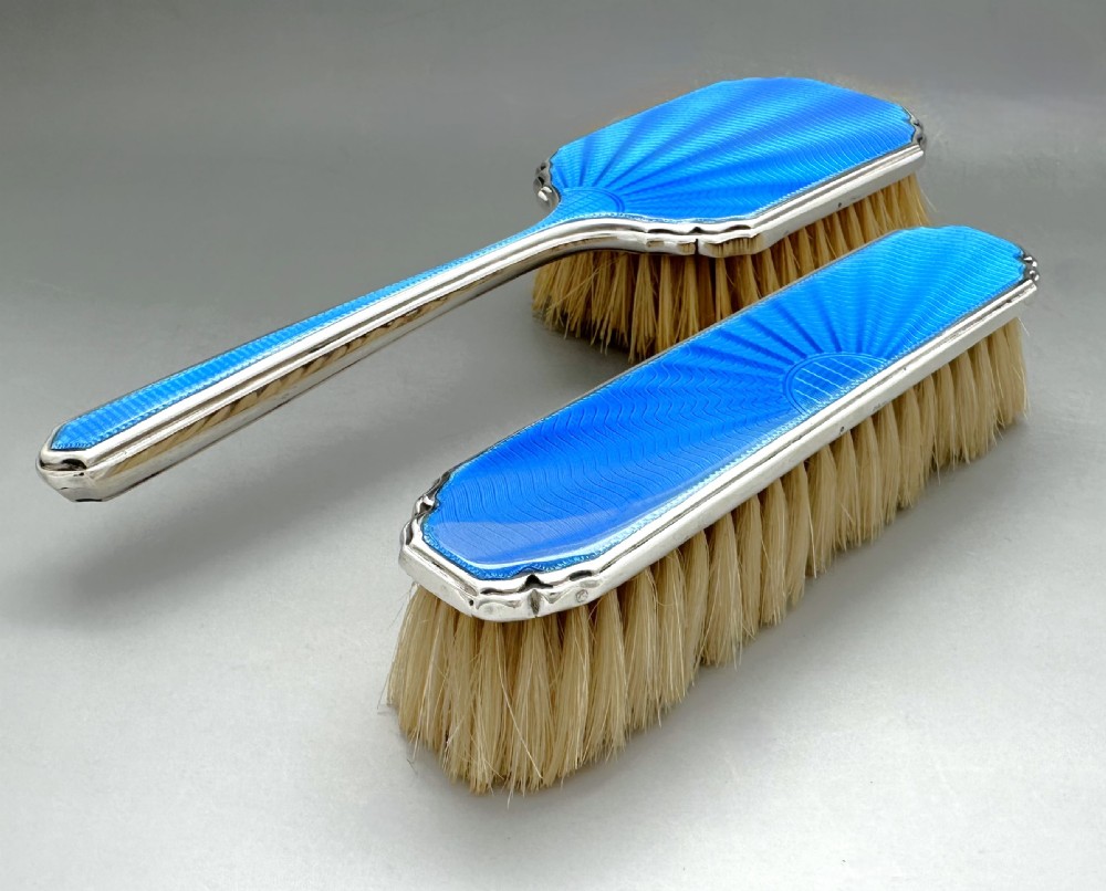A pair of Art Deco silver vanity brushes featuring bright blue sunburst guilloche enamel panels and natural light bristles. View III