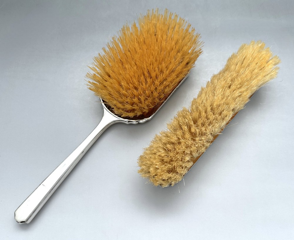 A pair of Art Deco silver vanity brushes featuring bright blue sunburst guilloche enamel panels and natural light bristles. View VI