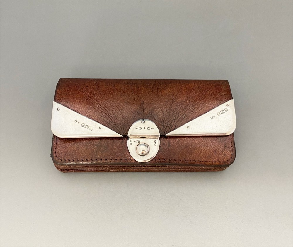 An Edwardian brown leather purse featuring hallmarked sterling silver corner mounts and a central silver clasp fastener.