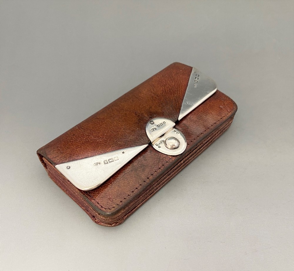 An Edwardian brown leather purse featuring hallmarked sterling silver corner mounts and a central silver clasp fastener. View II