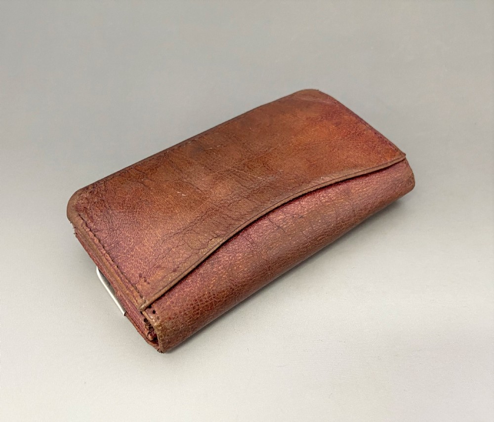 An Edwardian brown leather purse featuring hallmarked sterling silver corner mounts and a central silver clasp fastener. View V