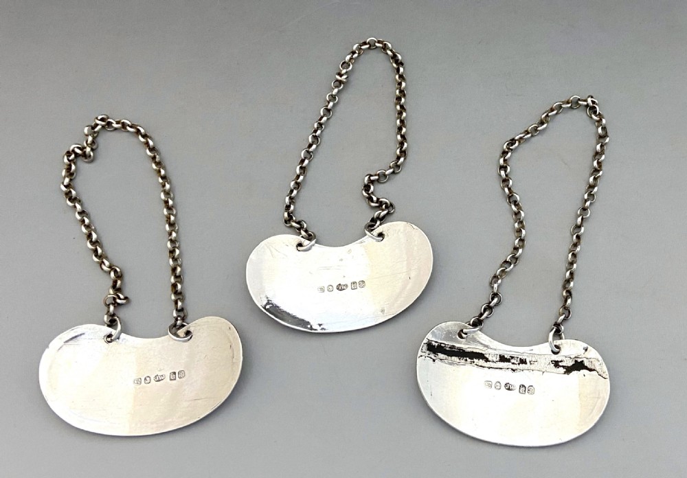 A set of three crescent shaped sterling silver decanter labels with chains, engraved with the words Port, Sherry, and Madeira. View III