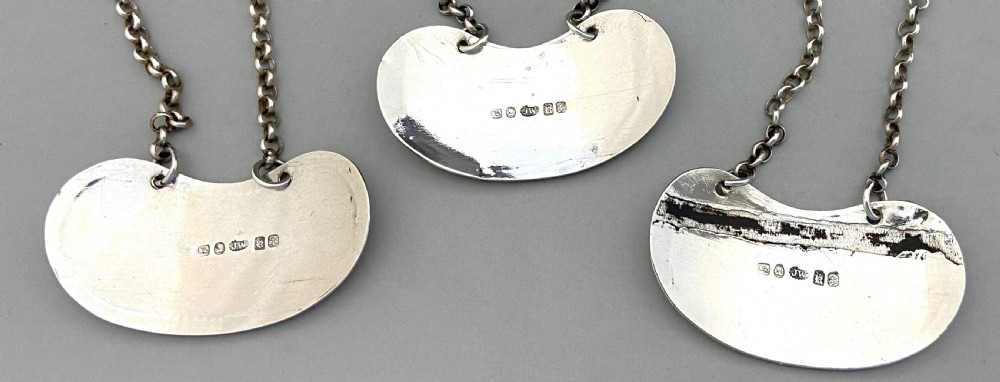 A set of three crescent shaped sterling silver decanter labels with chains, engraved with the words Port, Sherry, and Madeira. View IV