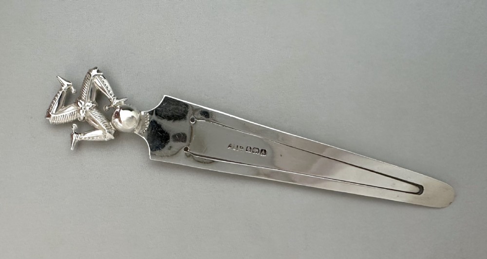A solid sterling silver bookmark featuring a cast Three Legs of Man triskelion finial and visible hallmarks on the tapered blade. View IV