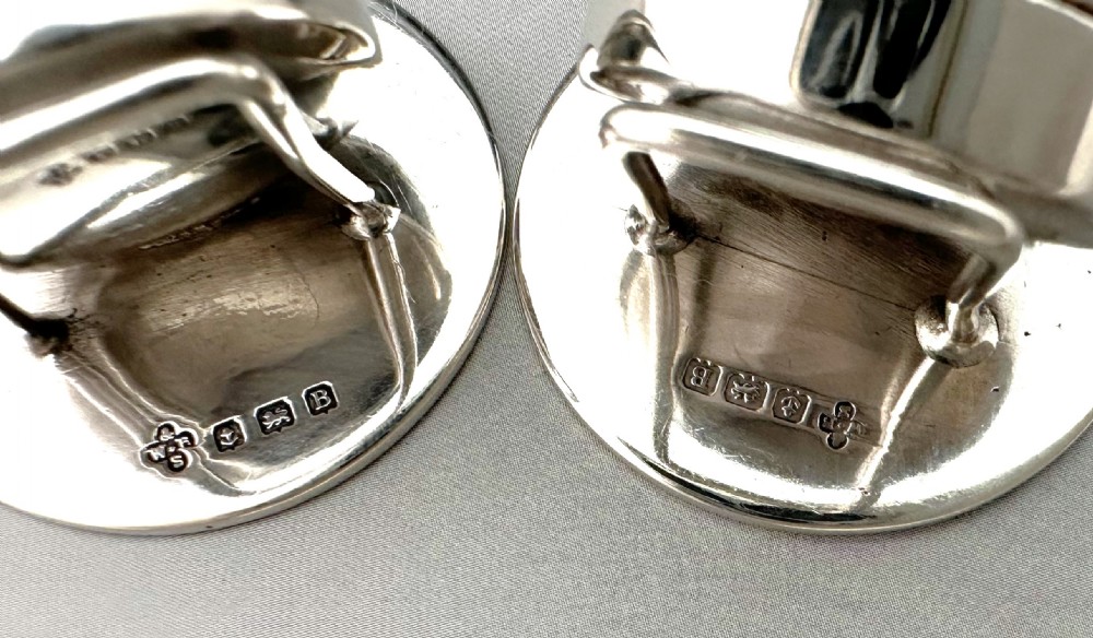 A pair of circular silver menu holders featuring deep blue enamelled centres set on flat round bases. View XII