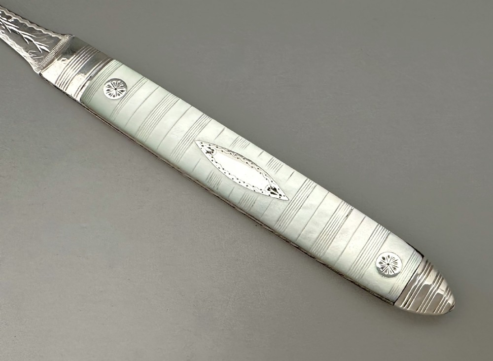 A late eighteenth-century silver folding fruit fork featuring engraved two-pronged tines and a decorated mother-of-pearl handle on a neutral background. View III