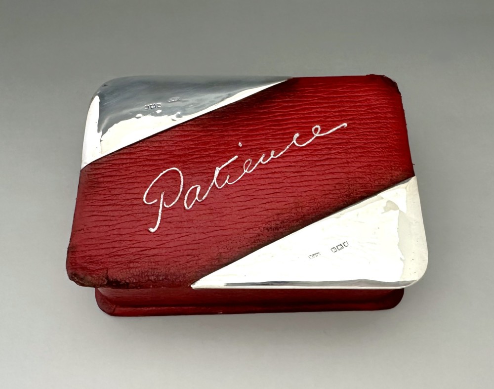 A rectangular red textured leather card box featuring silver corner mounts and silver script reading Patience across the top.