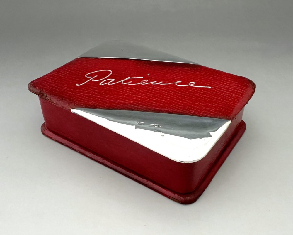 A rectangular red textured leather card box featuring silver corner mounts and silver script reading Patience across the top. View II