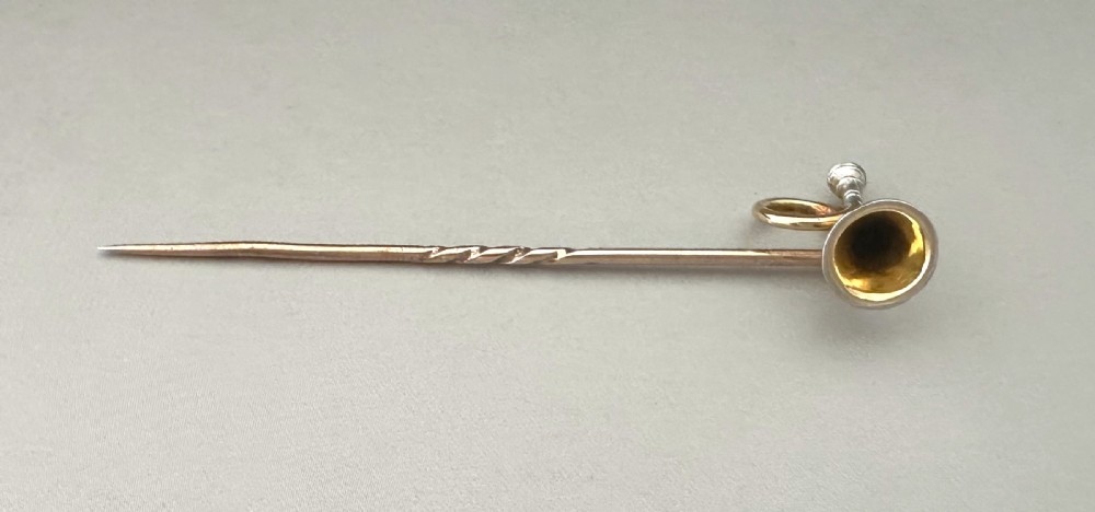 A 9ct gold Victorian stick pin featuring a detailed hunting horn motif, displayed inside a velvet-lined fitted presentation box. View III