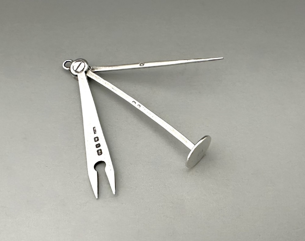 An antique Victorian sterling silver folding pipe tool featuring three implements attached to a central ring pivot with visible hallmarks.