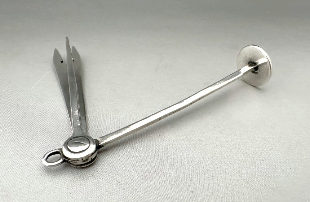 An antique Victorian sterling silver folding pipe tool featuring three implements attached to a central ring pivot with visible hallmarks. View IV