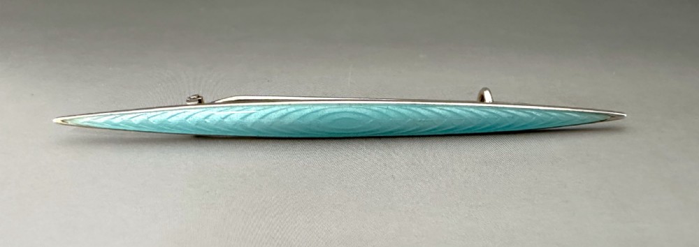 A slender Norwegian sterling silver bar brooch featuring light turquoise guilloche vitreous enamel over an engine-turned pattern. View VII