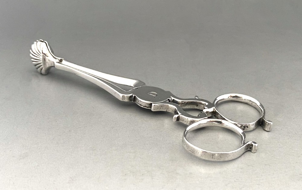 A pair of 18th-century silver scissor-action sugar nips with shell-shaped grips and an engraved monogram on the central pivot. View II