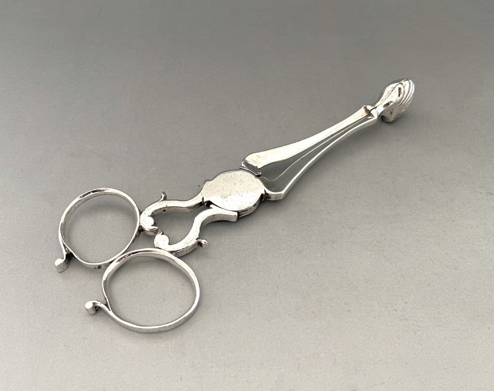 A pair of 18th-century silver scissor-action sugar nips with shell-shaped grips and an engraved monogram on the central pivot. View V