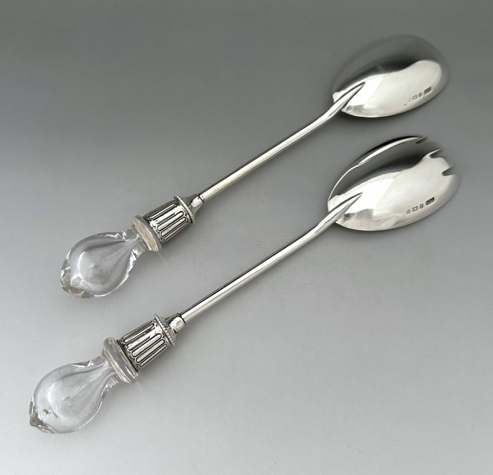 A pair of Edwardian silver salad servers featuring a rounded spoon and a three-pronged fork with decorative fluted ferrules and clear glass drop handles. View III