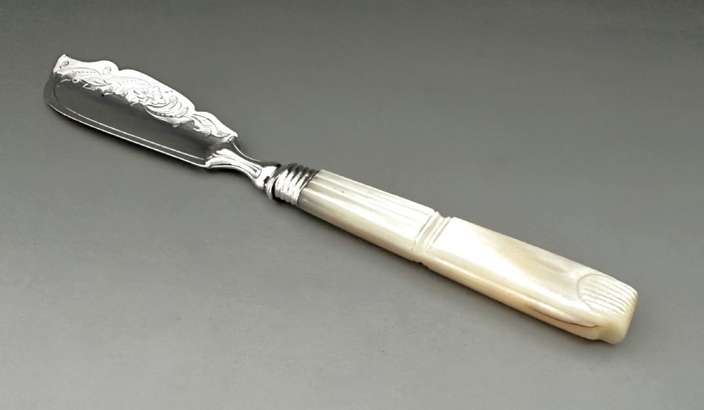 A Victorian silver butter knife featuring an engraved foliate blade and a carved mother-of-pearl handle. View II