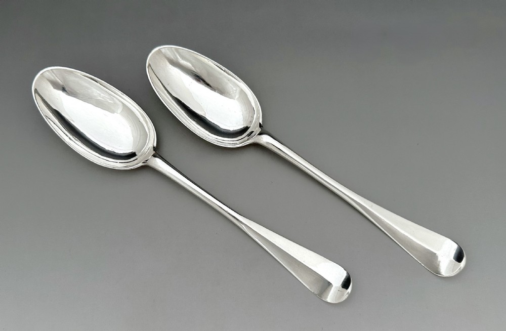 A pair of polished mid-18th-century Scottish sterling silver serving spoons with smooth oval bowls and slender stems resting on a neutral background. View II