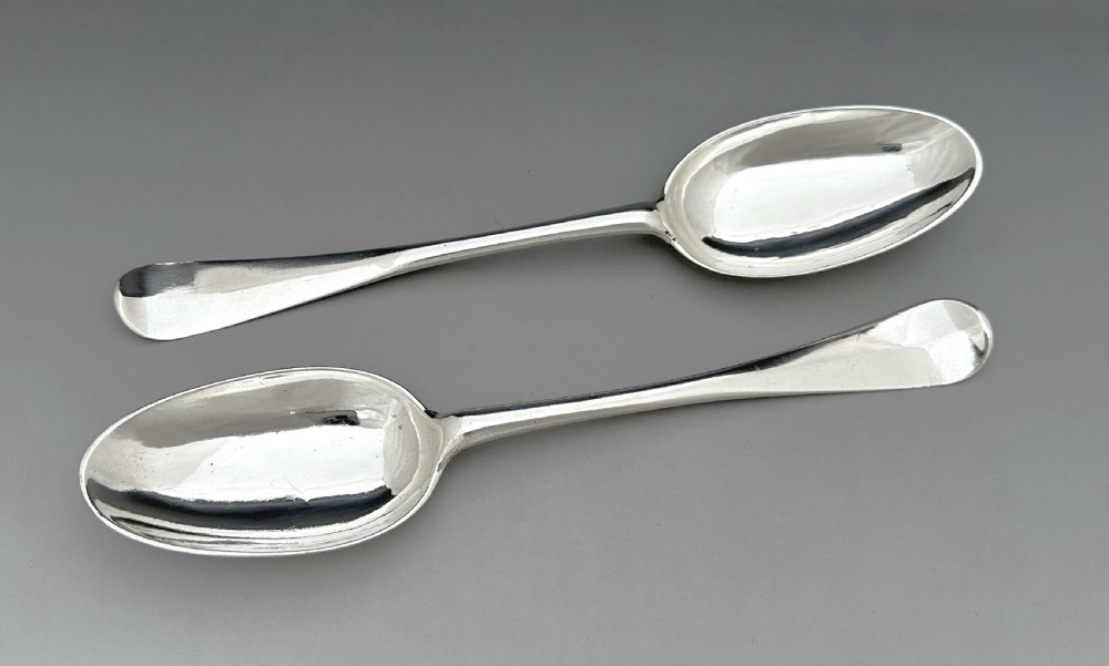 A pair of polished mid-18th-century Scottish sterling silver serving spoons with smooth oval bowls and slender stems resting on a neutral background. View III