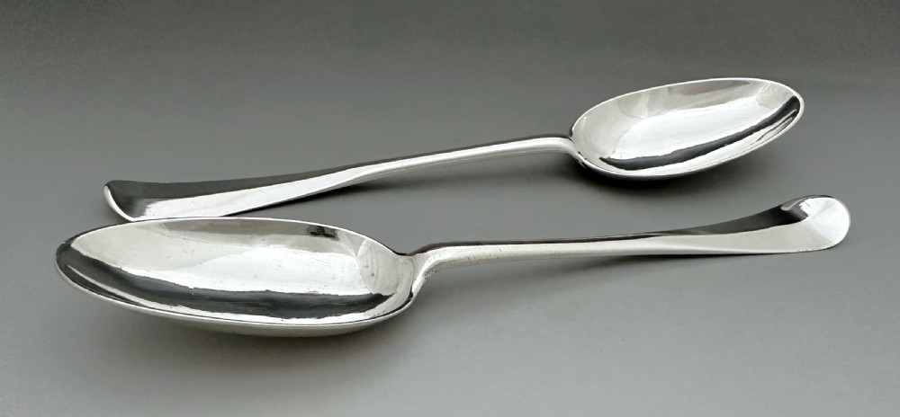 A pair of polished mid-18th-century Scottish sterling silver serving spoons with smooth oval bowls and slender stems resting on a neutral background. View V