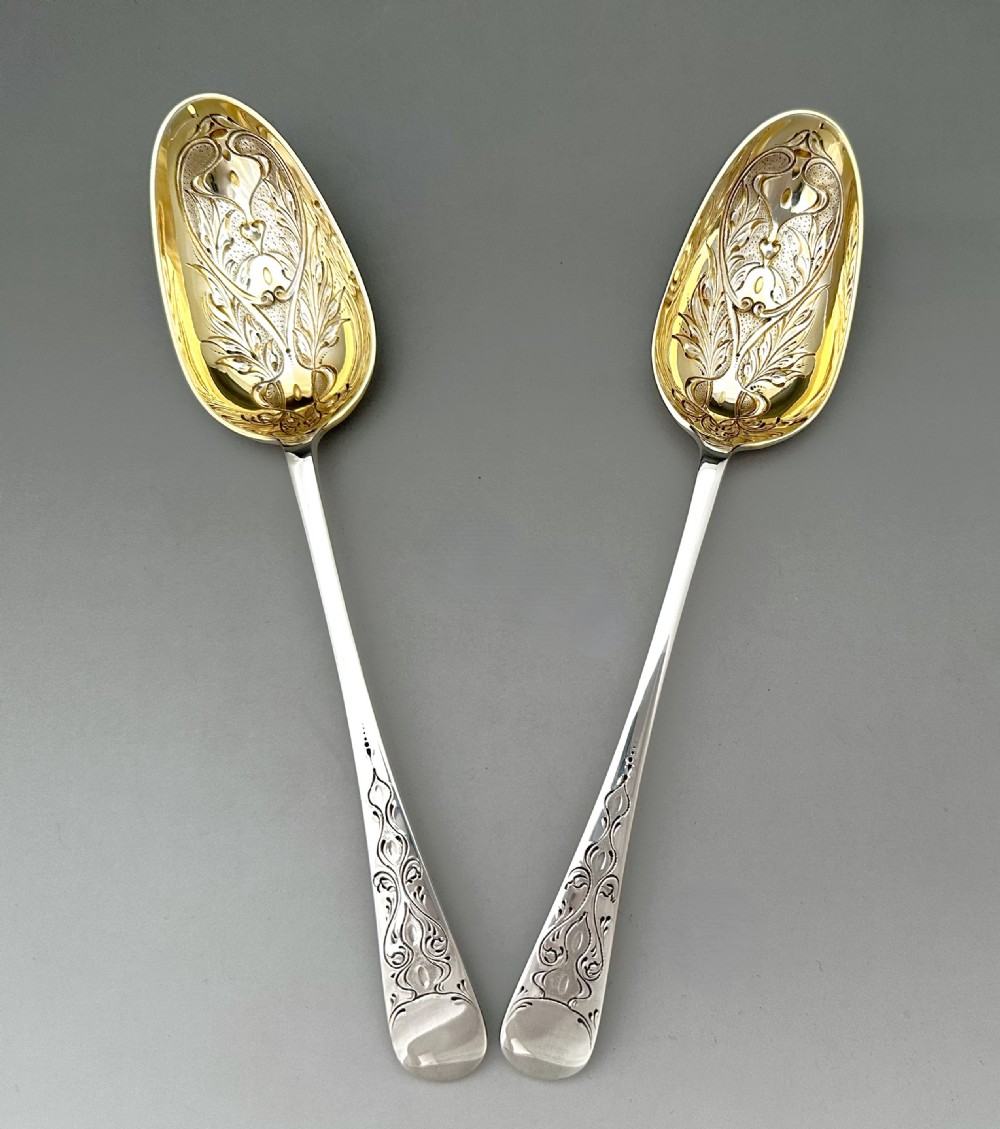 A pair of Art Nouveau sterling silver serving spoons with engraved foliate bowls and gold gilding, displayed in a red fitted velvet case. View V
