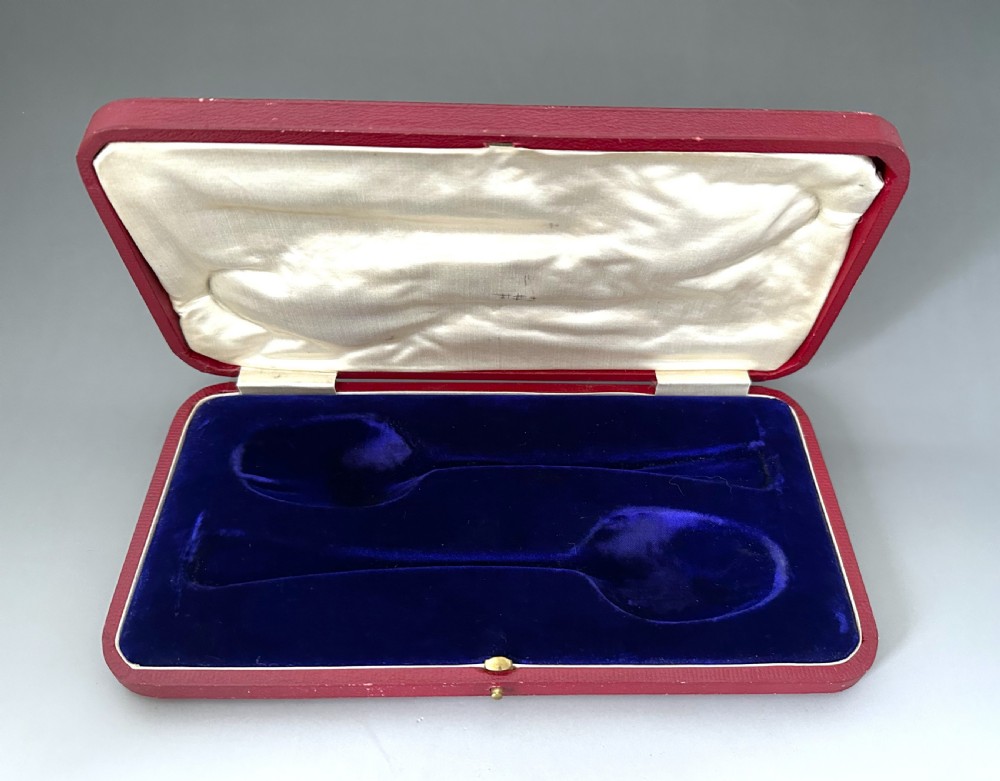 A pair of Art Nouveau sterling silver serving spoons with engraved foliate bowls and gold gilding, displayed in a red fitted velvet case. View VII