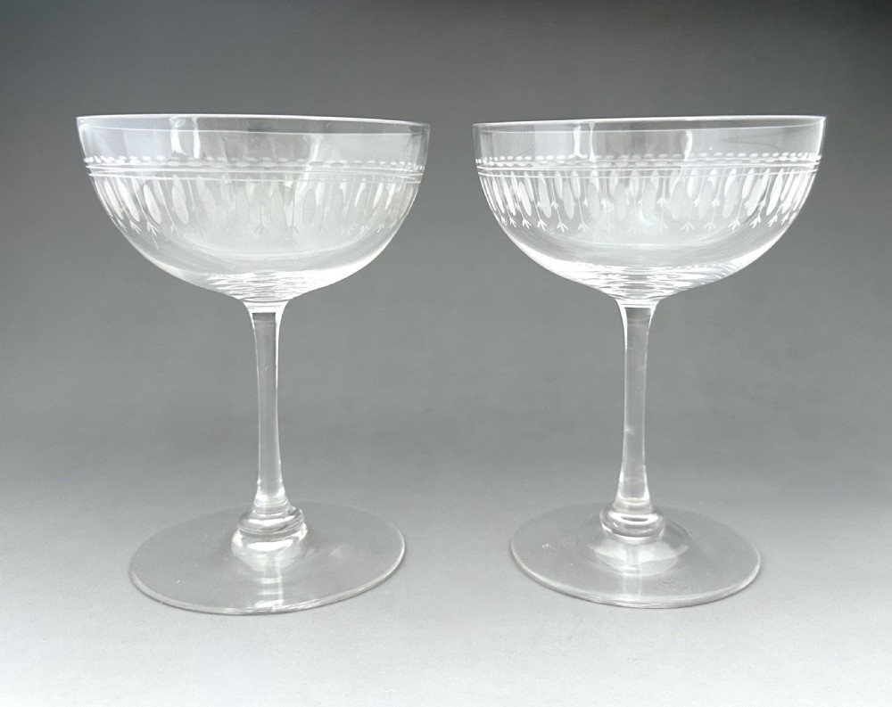A pair of clear glass Victorian champagne coupes featuring etched geometric border decorations and slender stems. View III