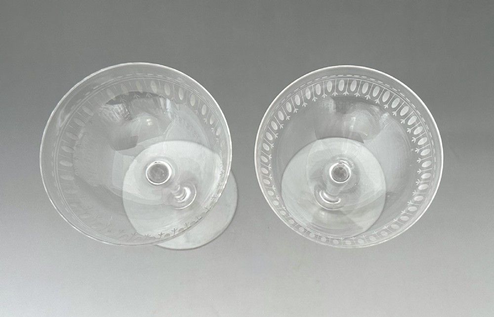 A pair of clear glass Victorian champagne coupes featuring etched geometric border decorations and slender stems. View IV