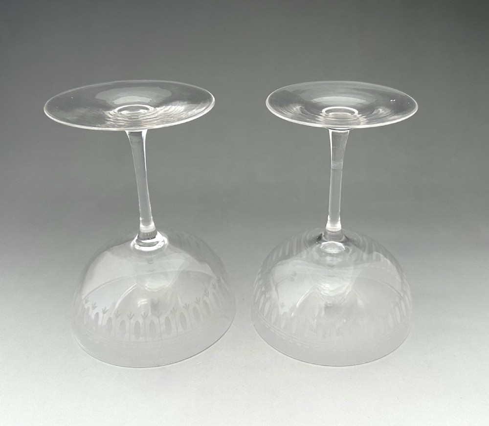 A pair of clear glass Victorian champagne coupes featuring etched geometric border decorations and slender stems. View V
