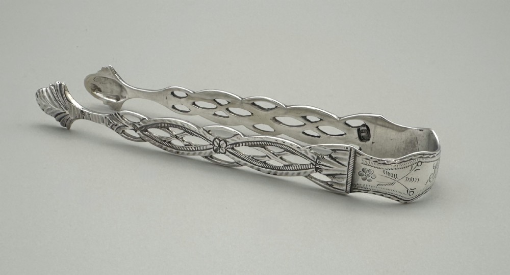 A pair of 18th-century cast sterling silver sugar tongs featuring openwork pierced lattice arms and shell-shaped grips.