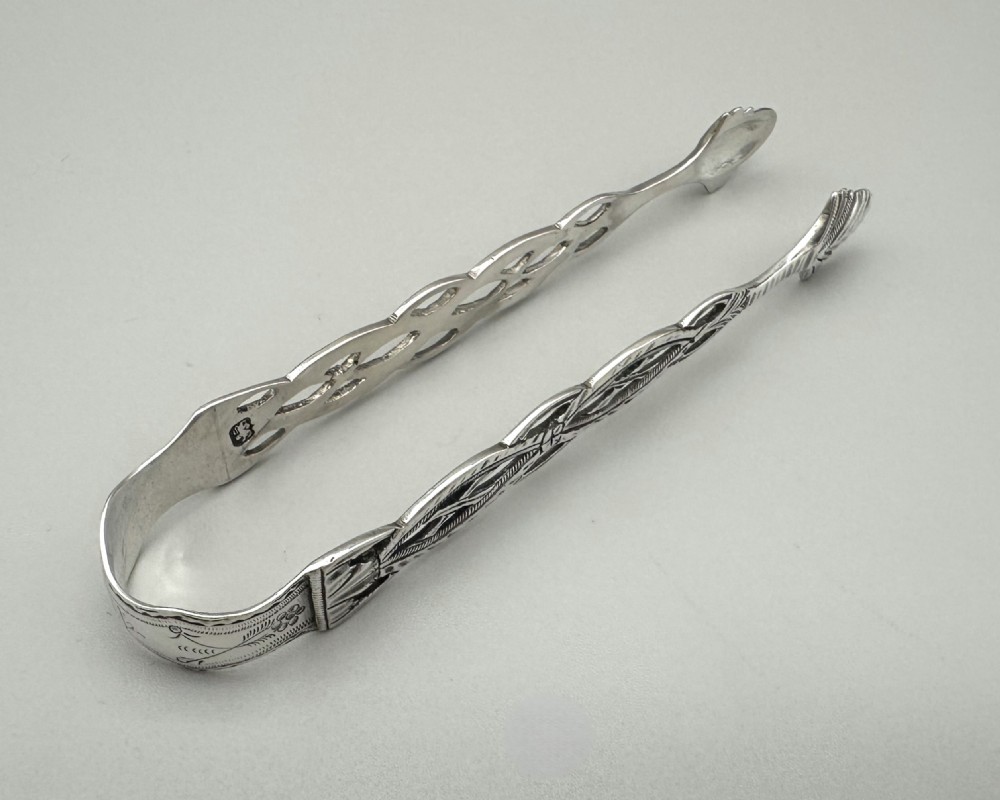 A pair of 18th-century cast sterling silver sugar tongs featuring openwork pierced lattice arms and shell-shaped grips. View III