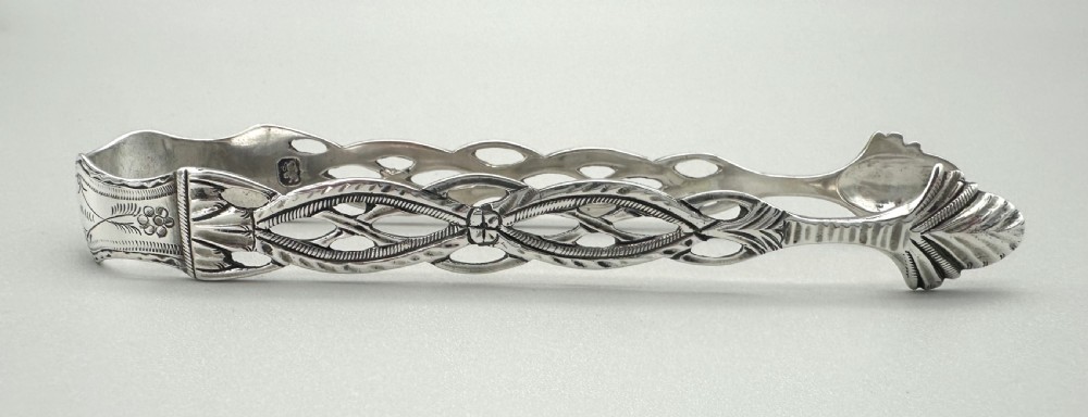 A pair of 18th-century cast sterling silver sugar tongs featuring openwork pierced lattice arms and shell-shaped grips. View IV