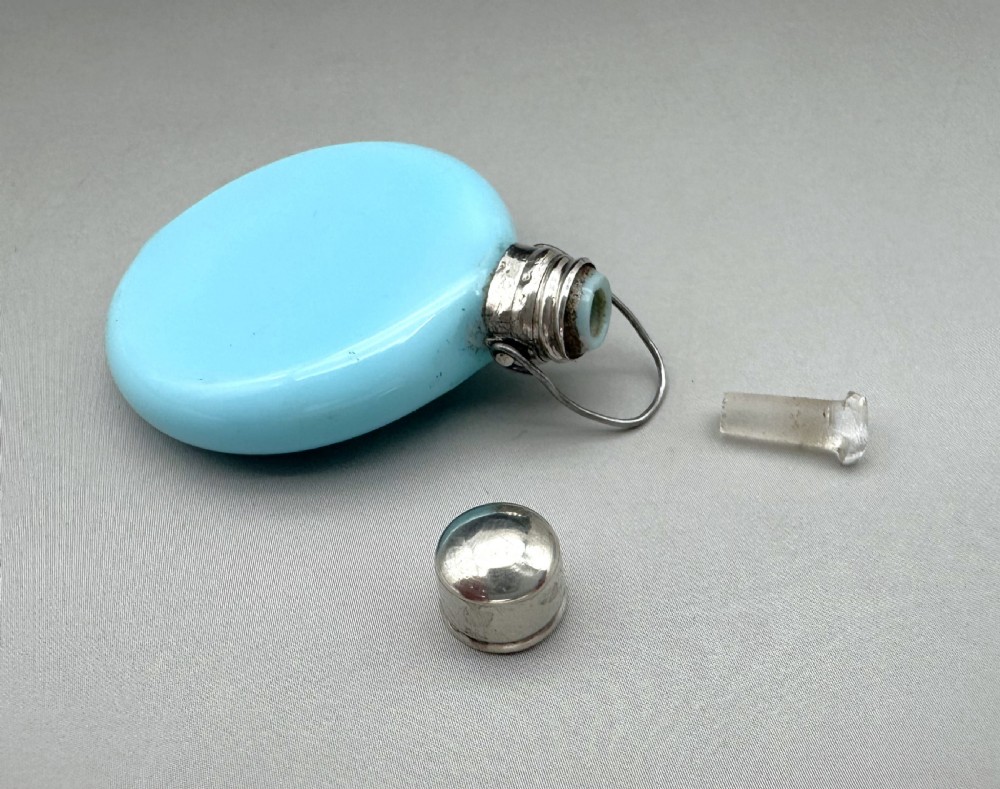 A circular light blue opaline glass scent bottle with a silver collar and hinged lid resting flat. View IV