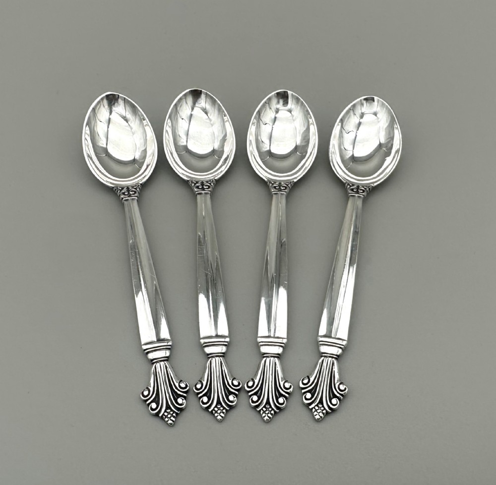 A set of four Danish sterling silver teaspoons with decorative carved scroll handles.