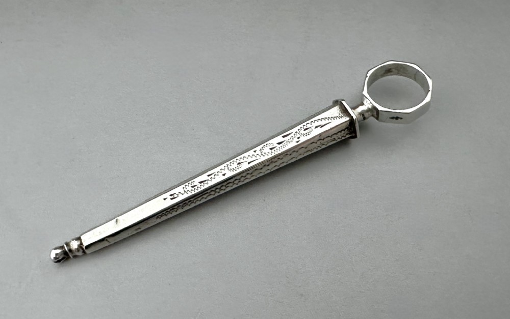 An antique Dutch silver sewing awl featuring a tapered engraved sheath and a pointed tool with a ring terminal. View II
