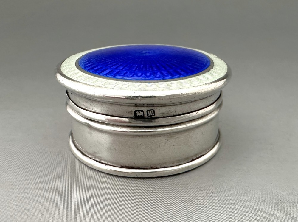 A circular sterling silver box with a brilliant blue guilloche enamel lid featuring radiating geometric patterns. View VII