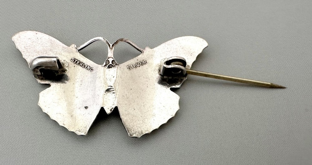 A silver butterfly brooch featuring yellow guilloche enamel wings and a dark central body. View V