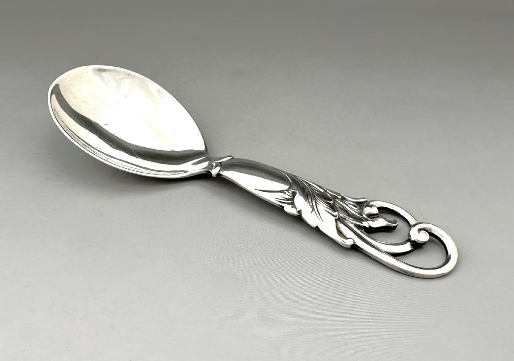 A Danish silver caddy spoon featuring a broad oval bowl and a handle decorated with carved foliage motifs and a scrolled terminal. View III