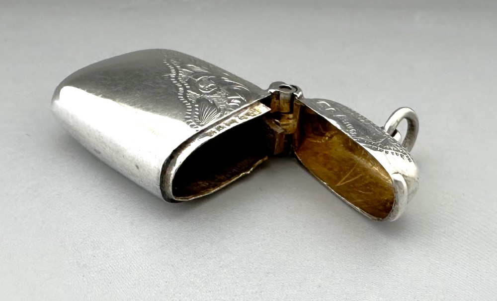 A small rectangular sterling silver vesta case featuring hand-engraved foliate decoration, a hinged lid, a suspension loop, and a serrated striker base. View IV