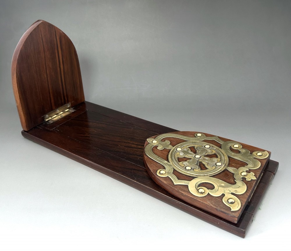 An extended wooden Victorian book slide with brass strapwork end panels holding a row of antique books. View II
