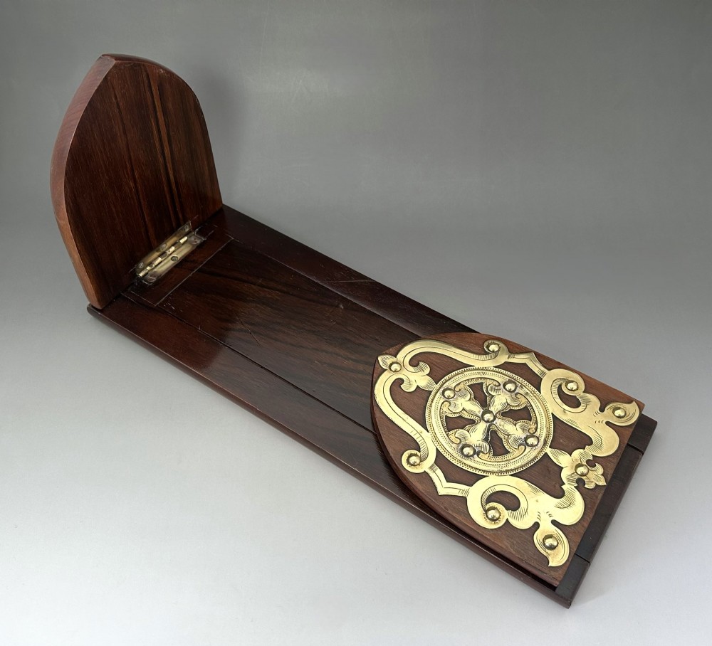 An extended wooden Victorian book slide with brass strapwork end panels holding a row of antique books. View III