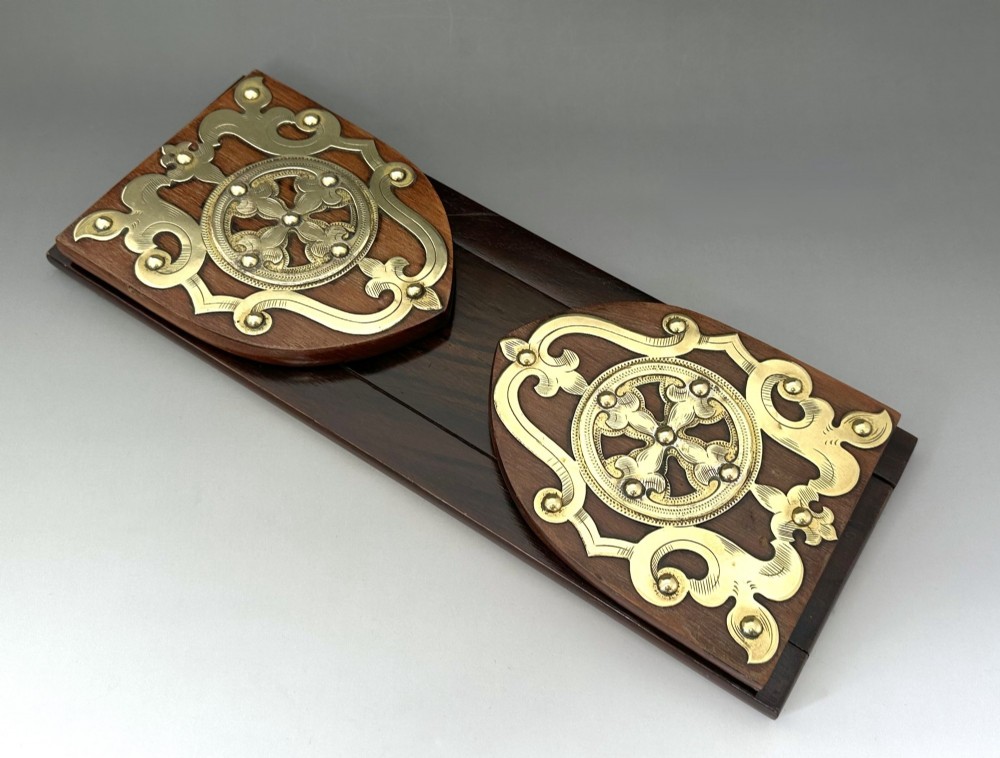 An extended wooden Victorian book slide with brass strapwork end panels holding a row of antique books. View IV