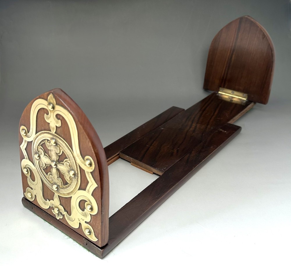 An extended wooden Victorian book slide with brass strapwork end panels holding a row of antique books. View V