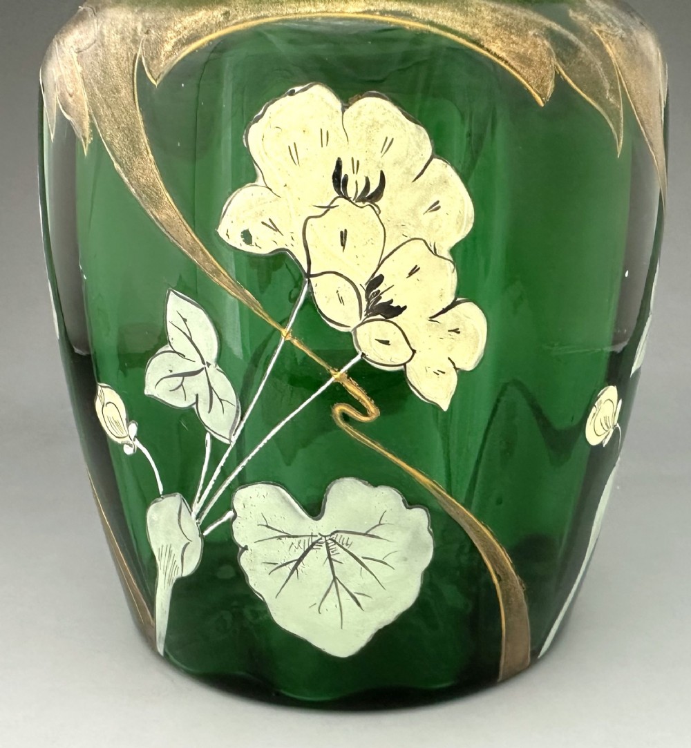 A green glass biscuit barrel featuring hand-painted white floral enamel and gold gilded leaf motifs with a matching glass lid. View IV
