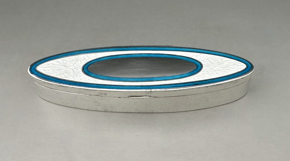 An elongated navette-shaped silver trinket box with concentric blue and white enamel borders over an engine-turned pattern. View II
