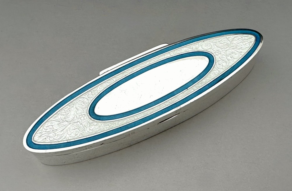 An elongated navette-shaped silver trinket box with concentric blue and white enamel borders over an engine-turned pattern. View III
