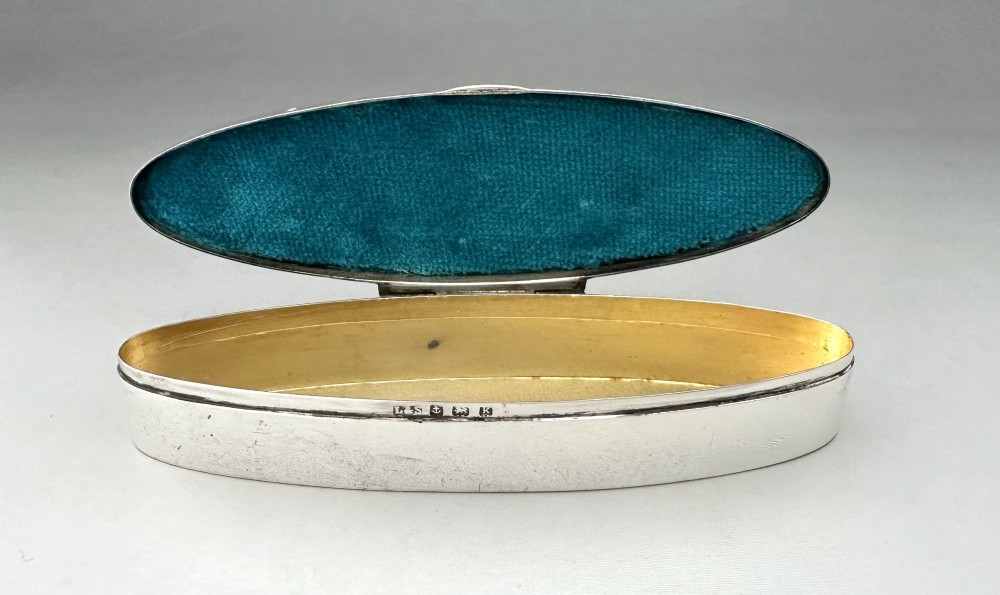 An elongated navette-shaped silver trinket box with concentric blue and white enamel borders over an engine-turned pattern. View VI