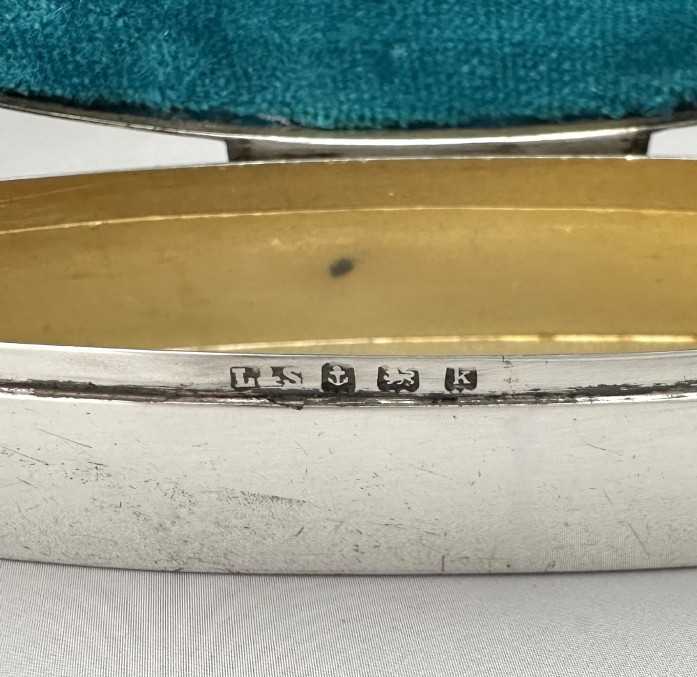 An elongated navette-shaped silver trinket box with concentric blue and white enamel borders over an engine-turned pattern. View VII